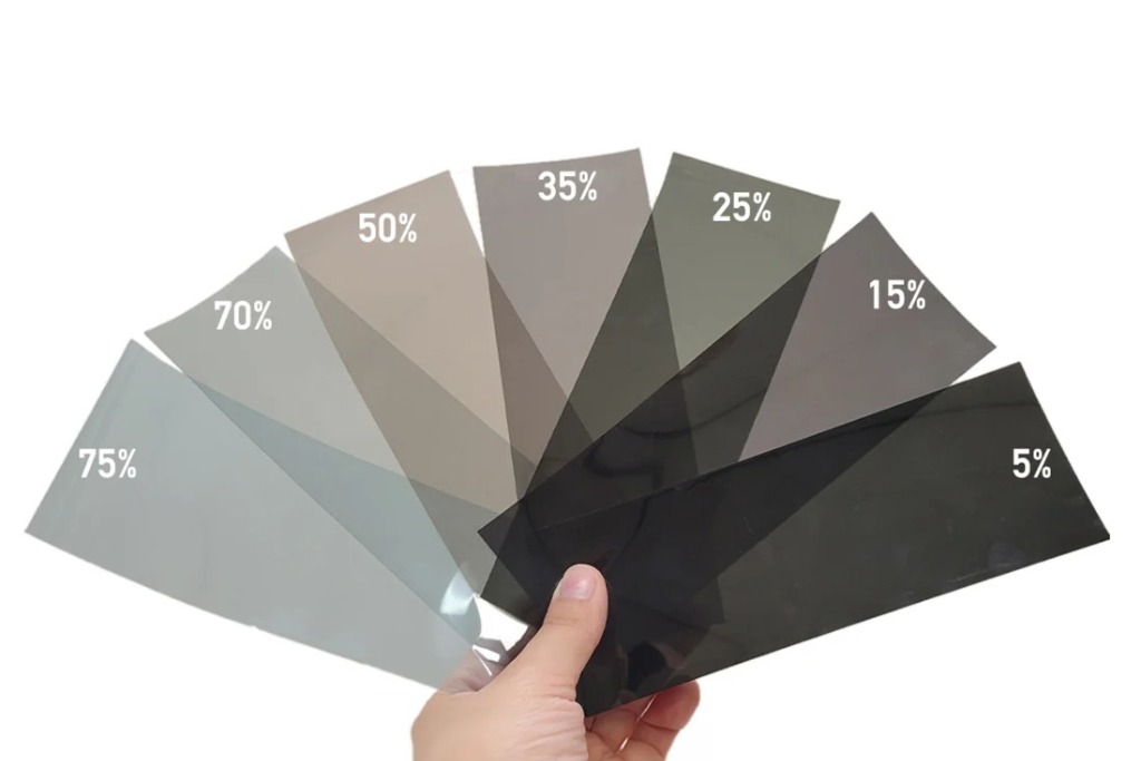 A hand holds a fan of car window tint samples labeled with various visible light transmission percentages from 75% to 5%, visually illustrating options for choosing the right tint at Exclusive Window Tinting NYC in Staten Island.