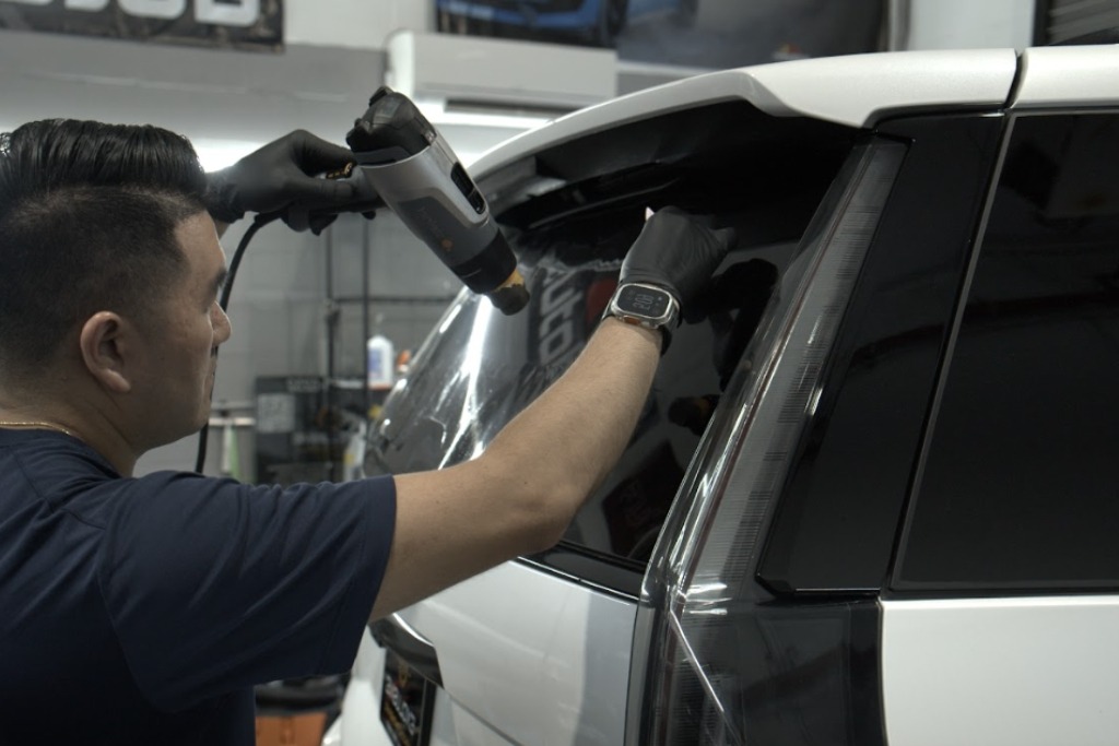 A technician at Exclusive Window Tinting NYC in Staten Island, NYC uses a heat gun to apply film to a rear SUV window, demonstrating expert care and why drivers should invest in quality tint for lasting performance and protection.